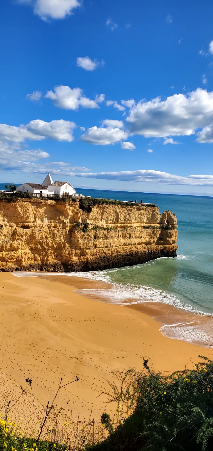 A small white chapel on a clifftop above an Algarve beach