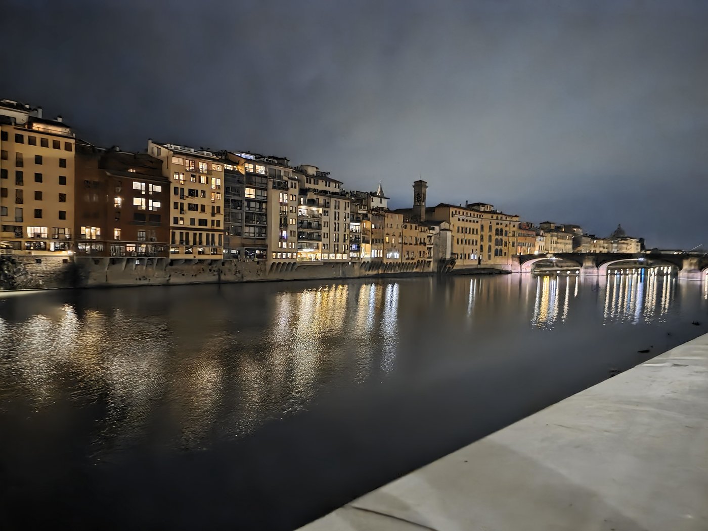 A European riverfront at night, lights reflected on the water