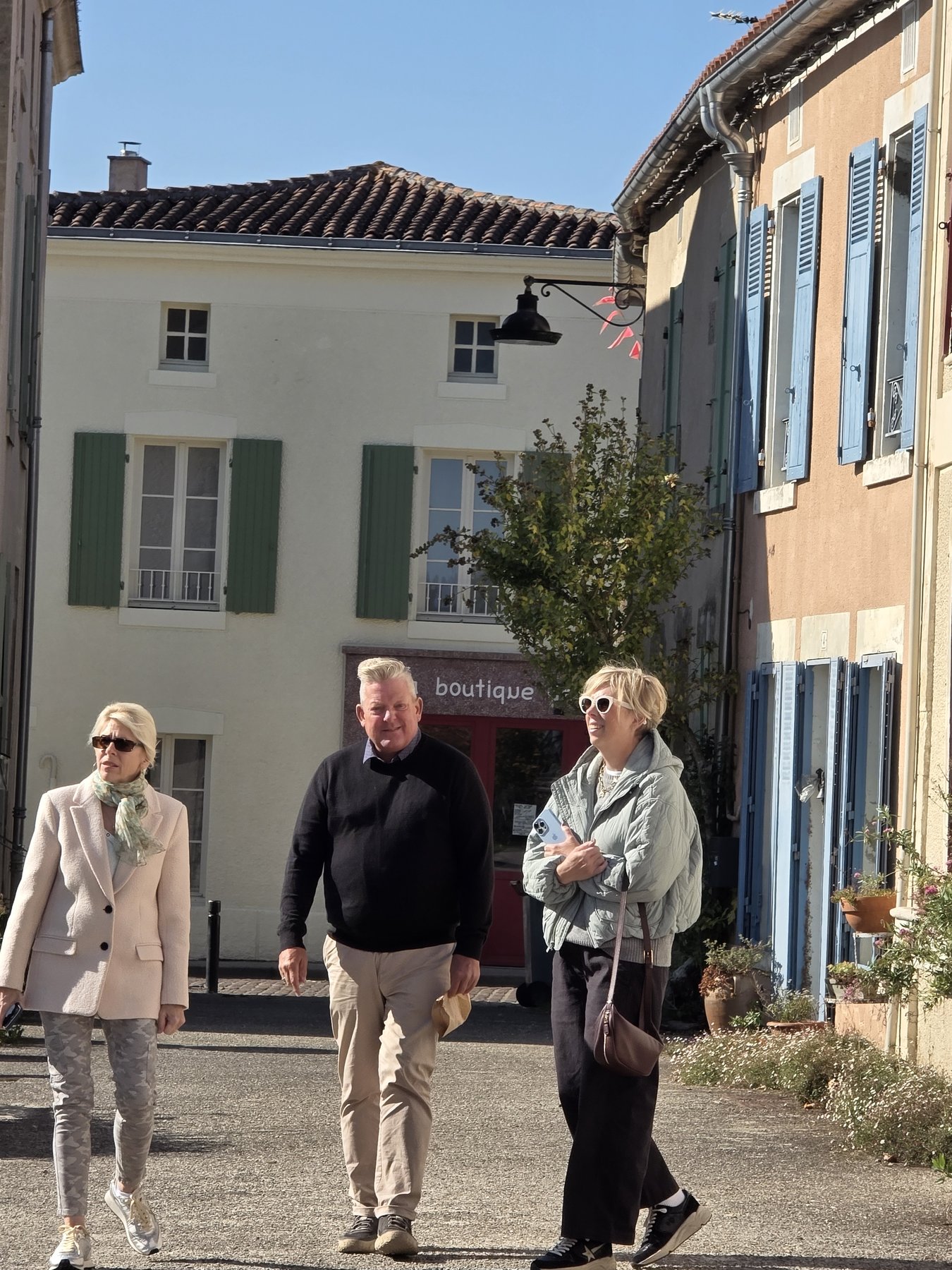 Arthur, John and a friend walking through a sunlit village street