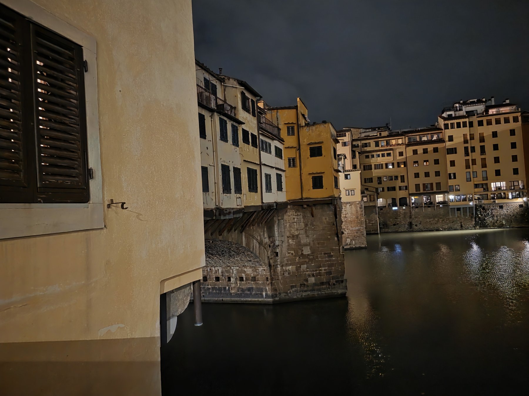 A European riverside town after dark, shutters and stone bridges
