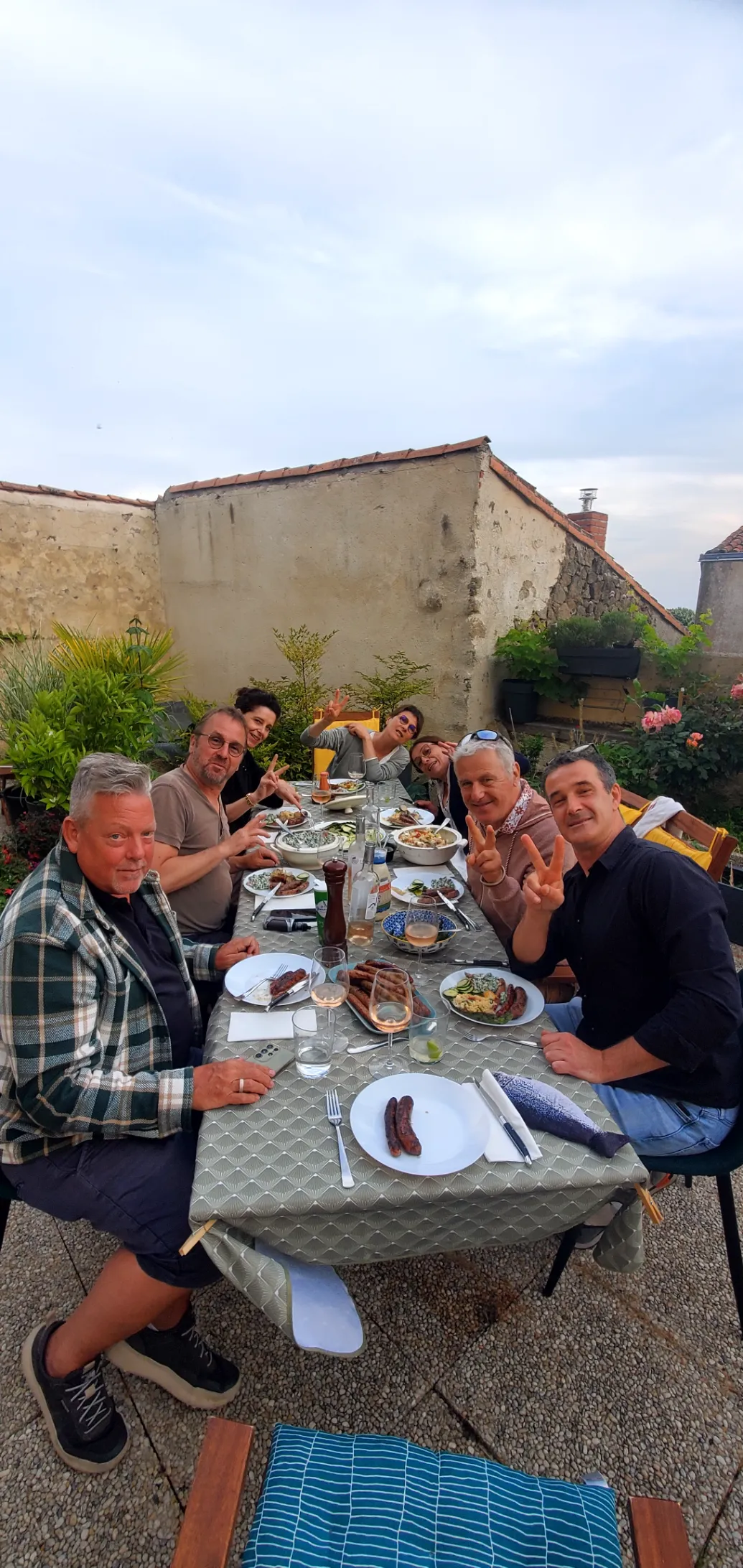 A long table on our terrace with friends, grilled sausages, wine, and salads